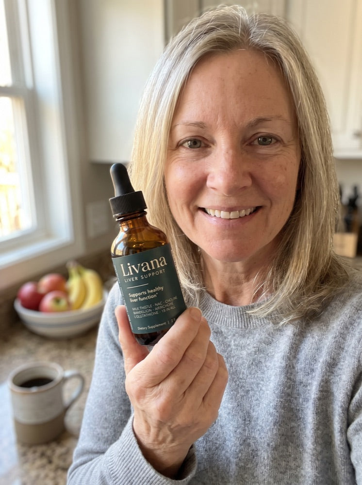 Dana holding her bottle of Livana in her kitchen