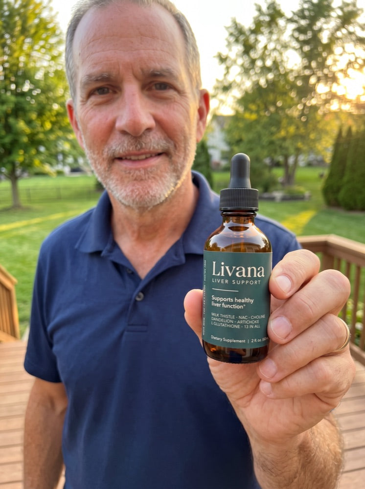 Greg holding up his bottle of Livana on his back patio