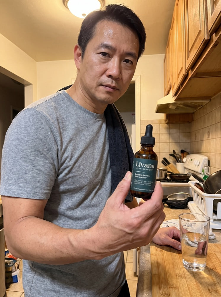 Kenji holding his bottle of Livana in his kitchen